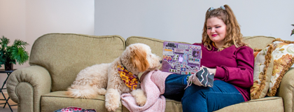 Emma Skogseth and her goldendoodle learning on Emma's couch.